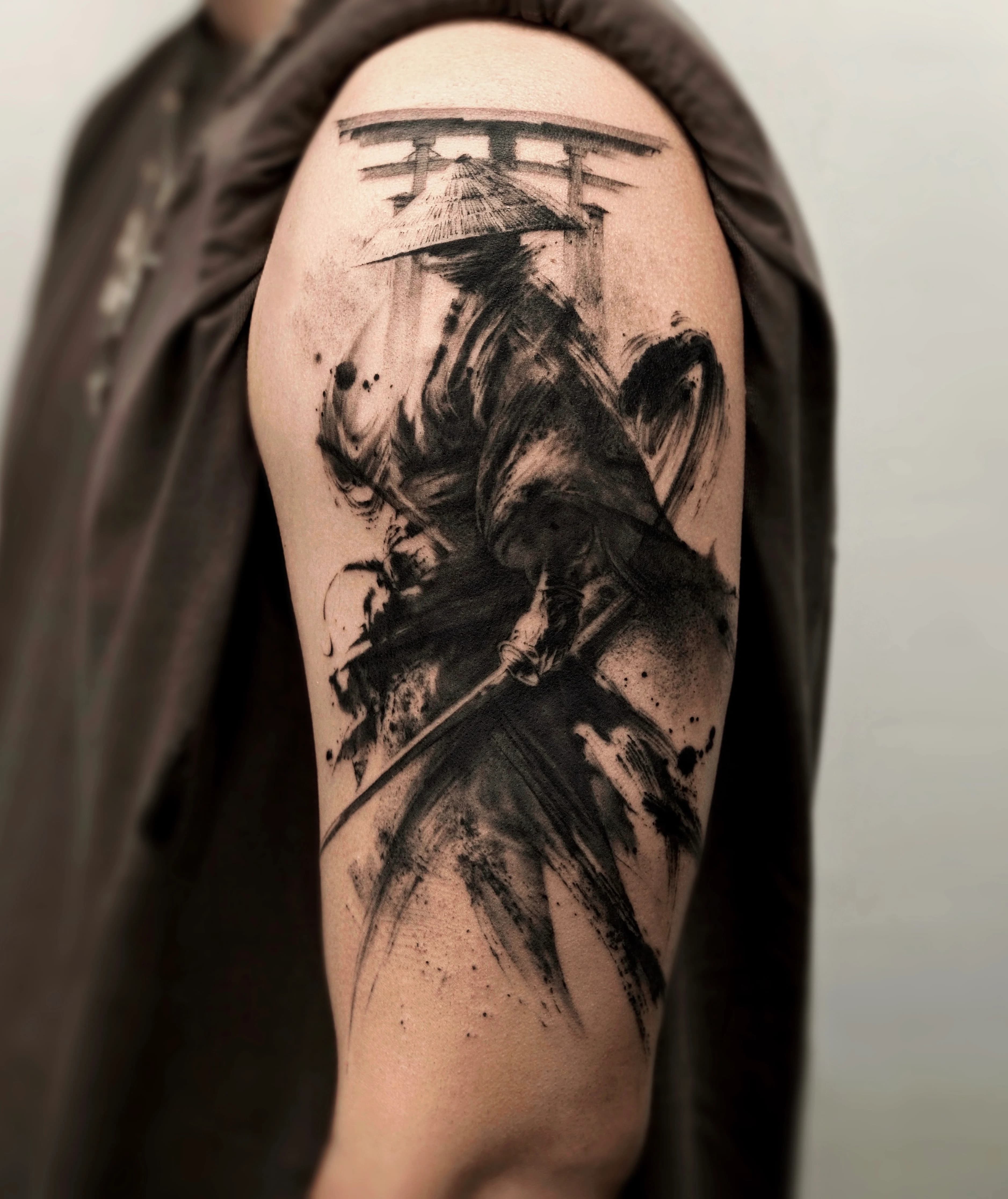 Ink brushstroke samurai tattoo on the upper arm with flowing cloth